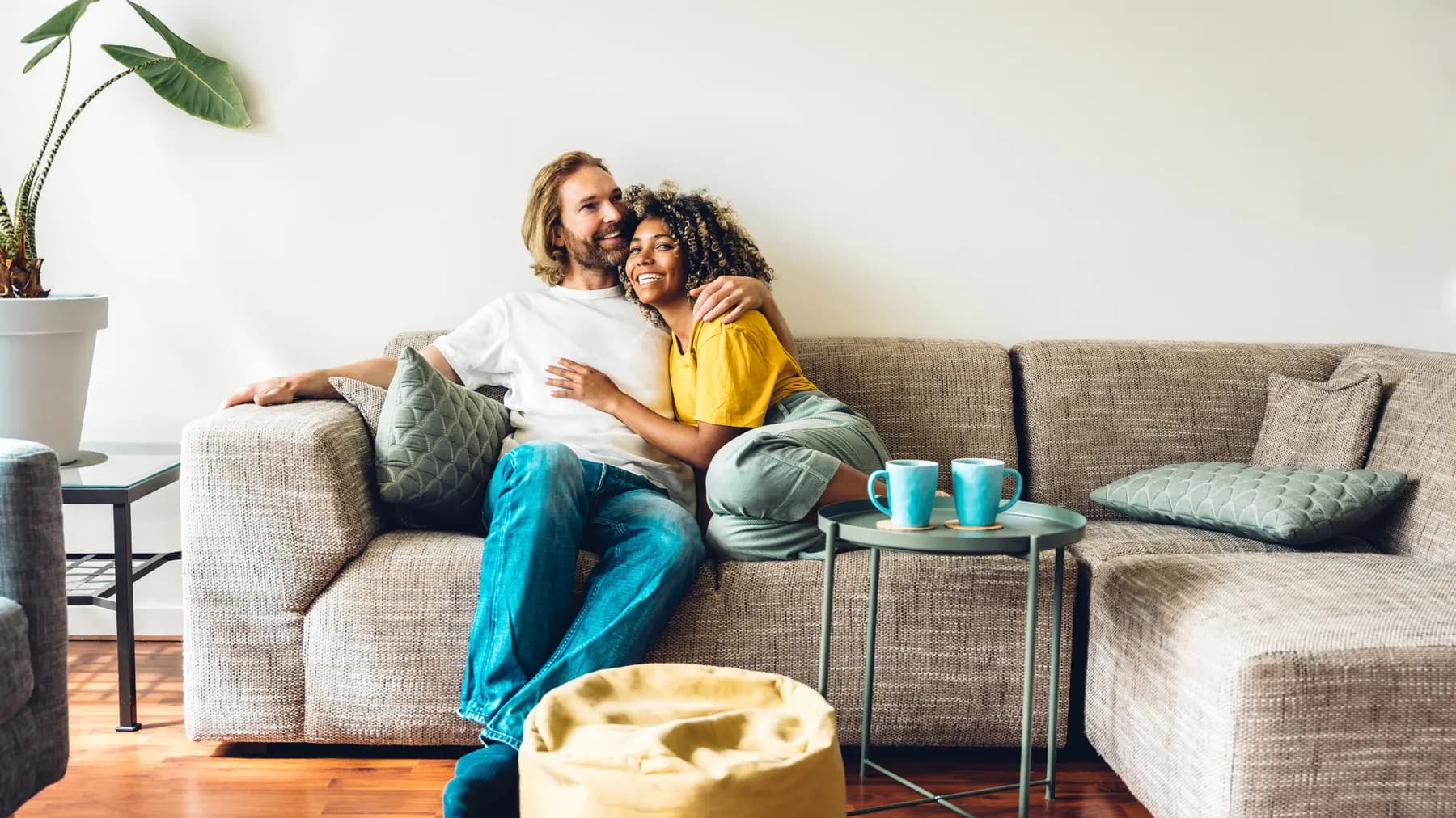 A couple relaxing together on their sofa with two mugs of coffee