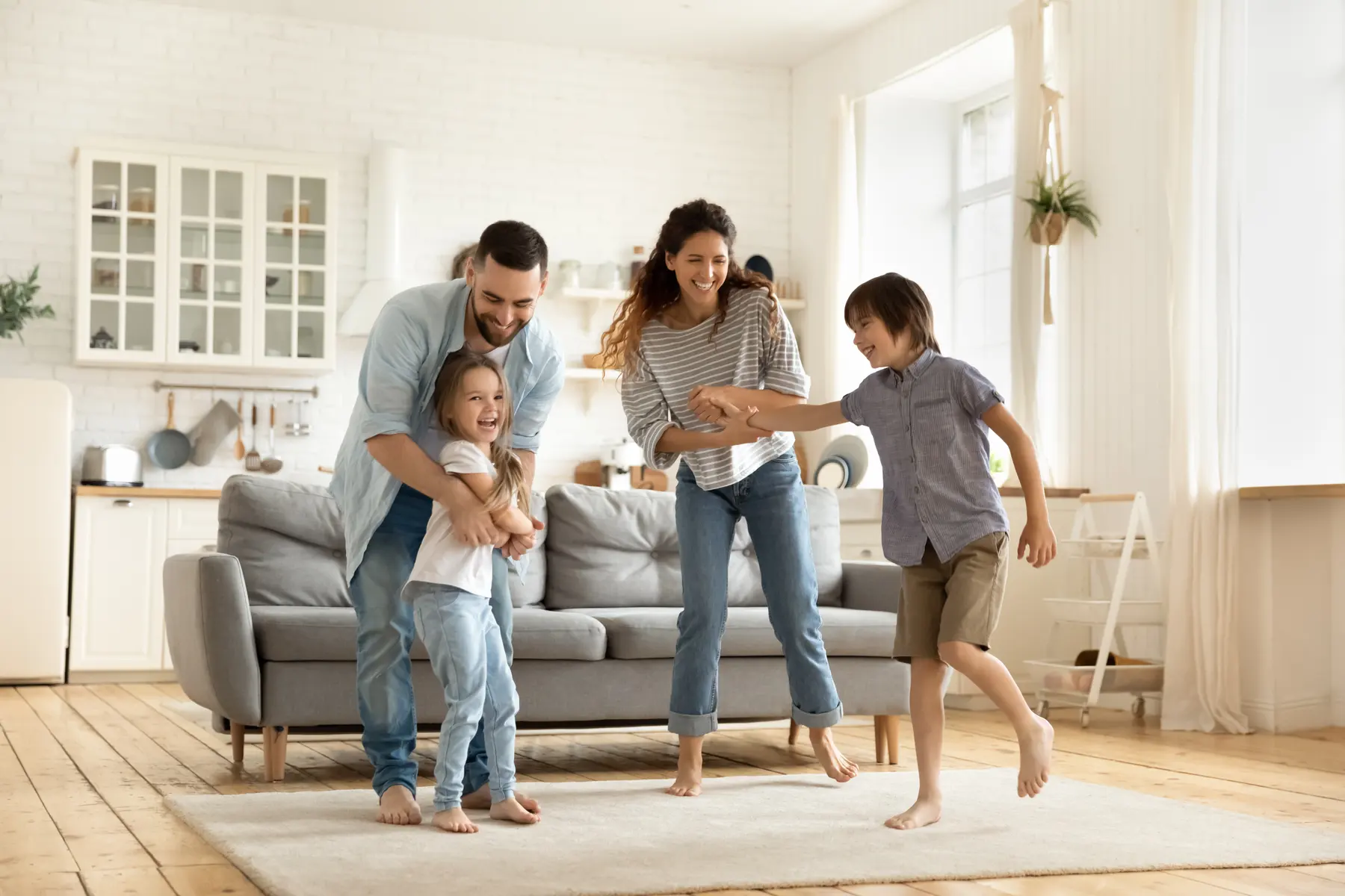 A family laughing and dancing barefoot in a bright living room